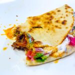 pulled beef taco, kjent som taco barbacoa, i hjemmelaget tortilla med rømme, syltet rødløk, paprika og koriander